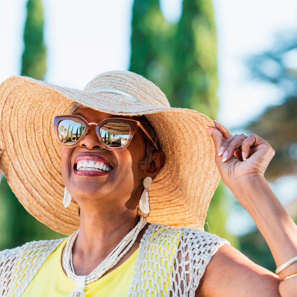 a woman smiles outside while wearing a sun hat